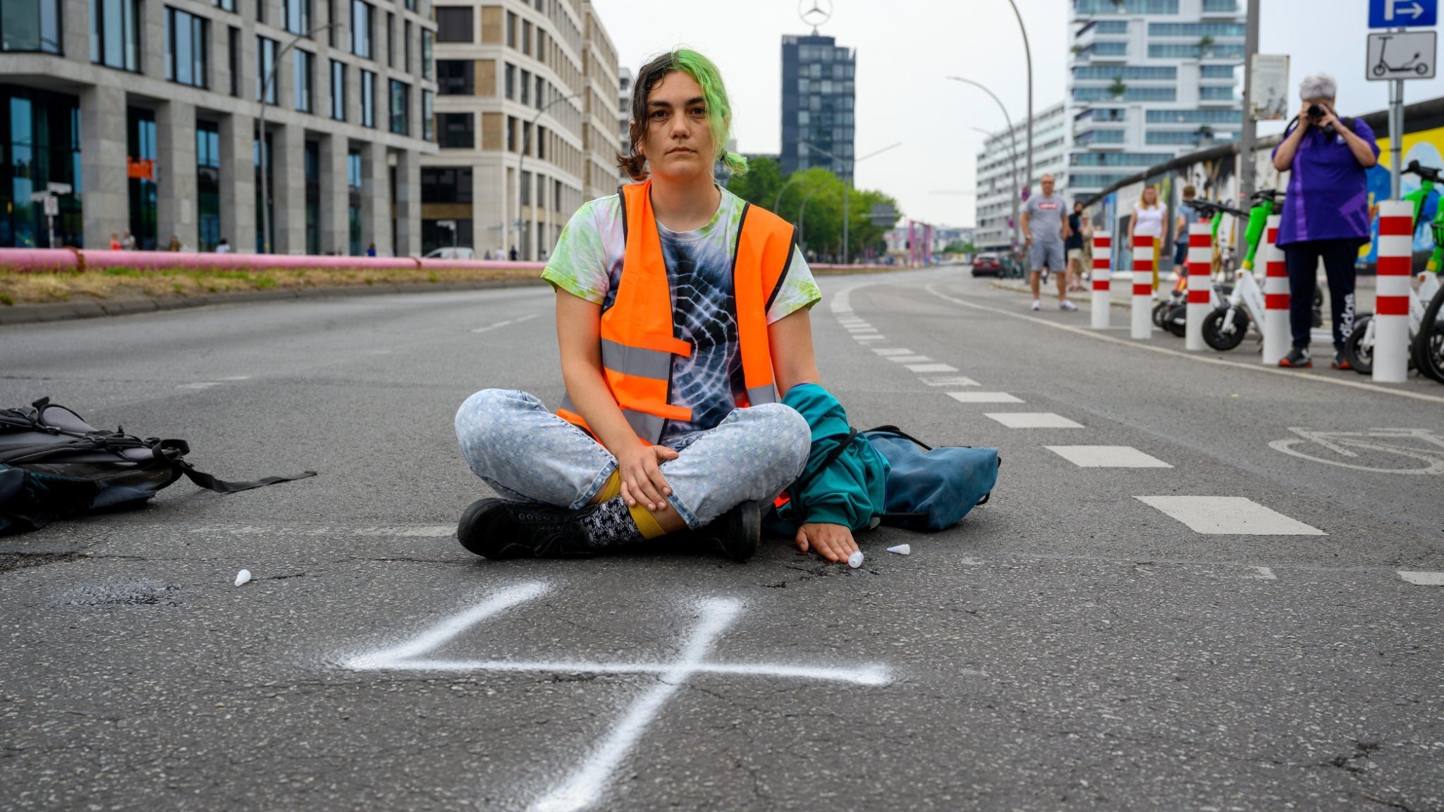 Eine Aktivistin der Letzten Generation blockiert eine Zufahrtsstraße zum Tag der Industrie in der Verti Music Hall, beim dem auch Olaf Scholz sprechen wird. Mühlenstraße, Berlin, 19.06.2023.