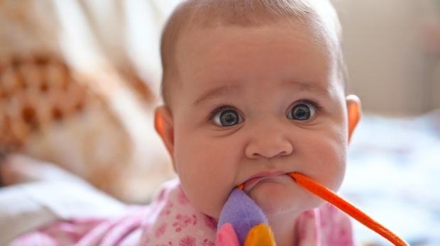 Baby mit Spielzeug im Mund