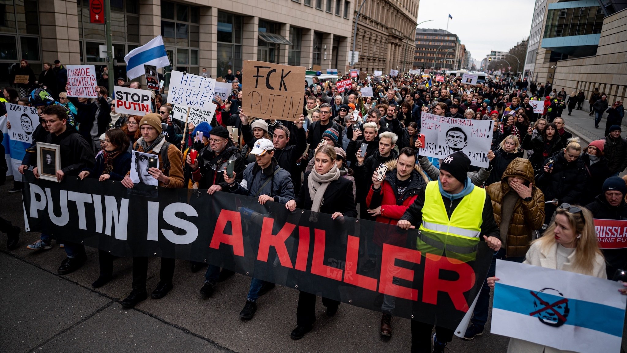 Menschen demonstrieren nach dem Tod des Regimekritikers Nawalny gegen die russische Regierung mit einem Banner mit der Aufschrift "Putin is a killer" in Berlin-Mitte.