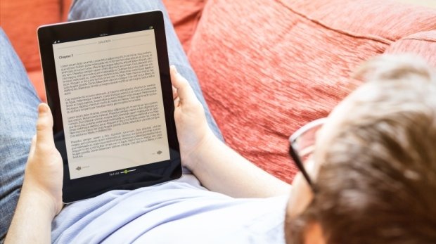 Mann liest E-Book auf Tablet