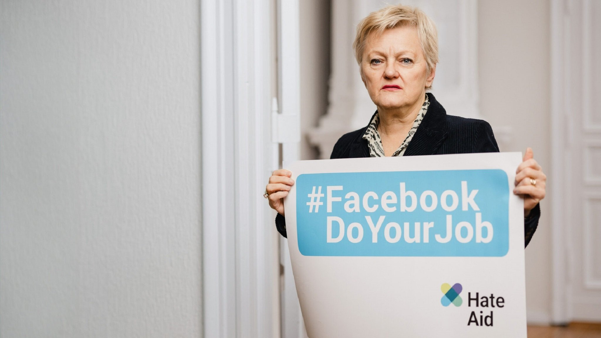 Renate Künast hält ein Plakat hoch: "Facebook Do Your Job"