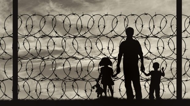 Silhouette einer Flüchtlingsfamilie hinter einem Zaun