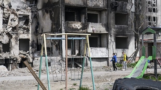 Jungen vor zerstörten Gebäuden in dern Nähe von Kiew