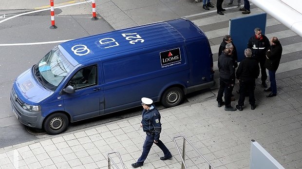 Polizisten und Mitarbeiter einer Sicherheitsfirma stehen an einem überfallenen Geldtransporter am Flughafen Köln/Bonn. 06.03.2019.