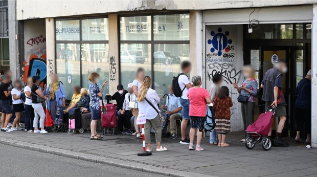 Menschen stehen in einer Schlange und warten vor einem Tafelladen, 21.7.2022