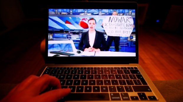 Die Abendnachrichten des wichtigsten russischen Nachrichtensenders, Kanal 1, werden auf einem Laptop gezeigt, als sie von einer Frau unterbrochen werden, die gegen den Krieg in der Ukraine protestiert.
