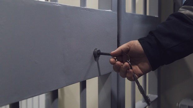 Beamter verschließt eine Türe im Gefängnis.