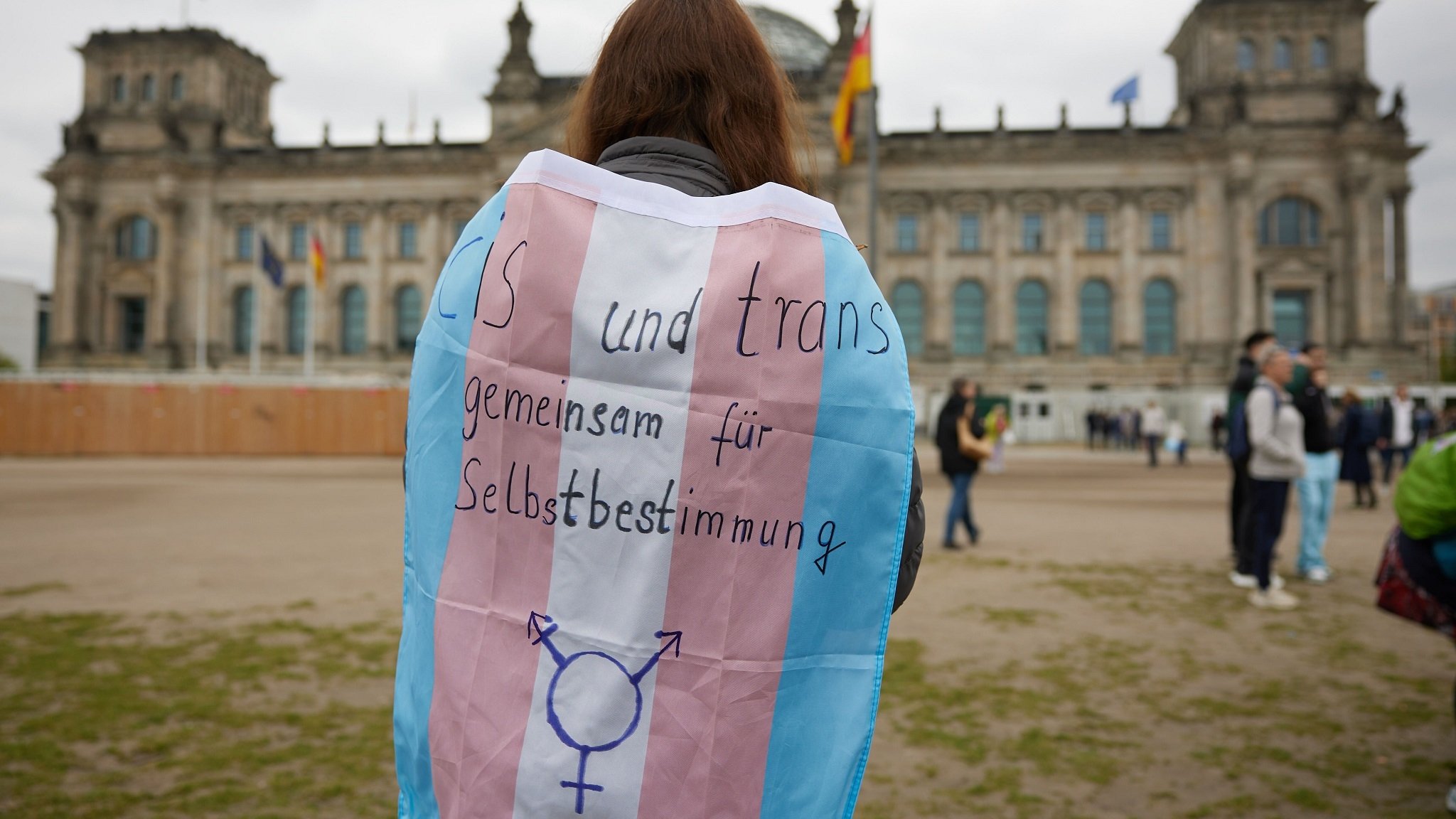 Demonstrantin mit Flagge "Cis und trans: gemeinsam für Selbstbestimmung"