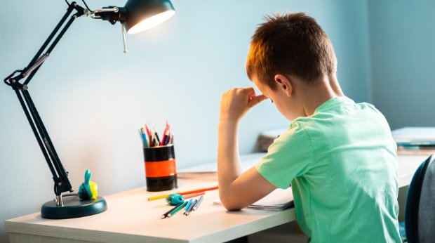 Ein Junge macht Hausaufgaben zu Hause an seinem Schreibtisch (Symbolbild)