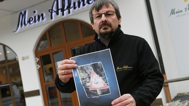Der Geschäftsführer des Tölzer Kasladen, Wolfgang Hofmann steht mit einem Foto der Protestschilder vor seinem Laden.