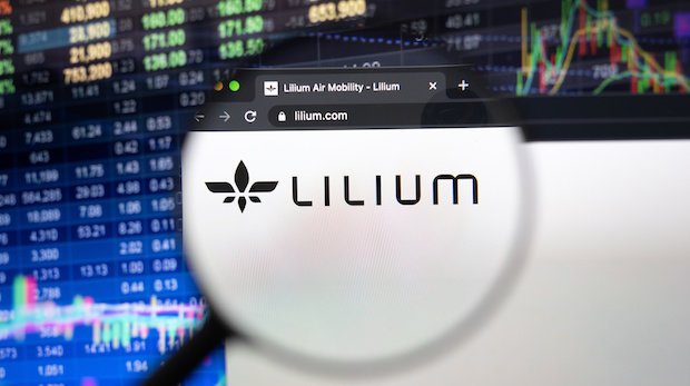 Lilium-Logo auf Webseite mit Börsen-Kurstafel als verschwommenem Hintergrund