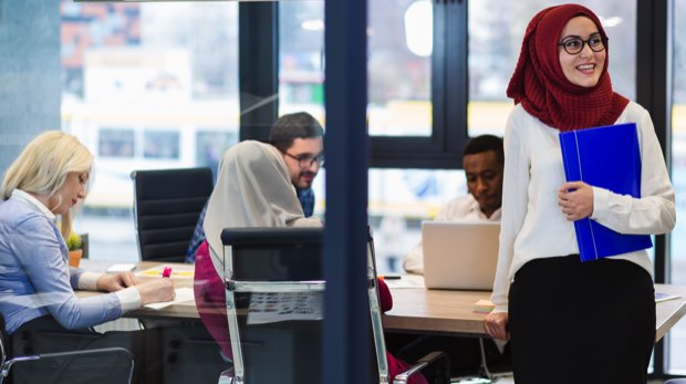Eine Gruppe bei der Arbeit im Büro, zwei Frauen tragen Kopftücher.