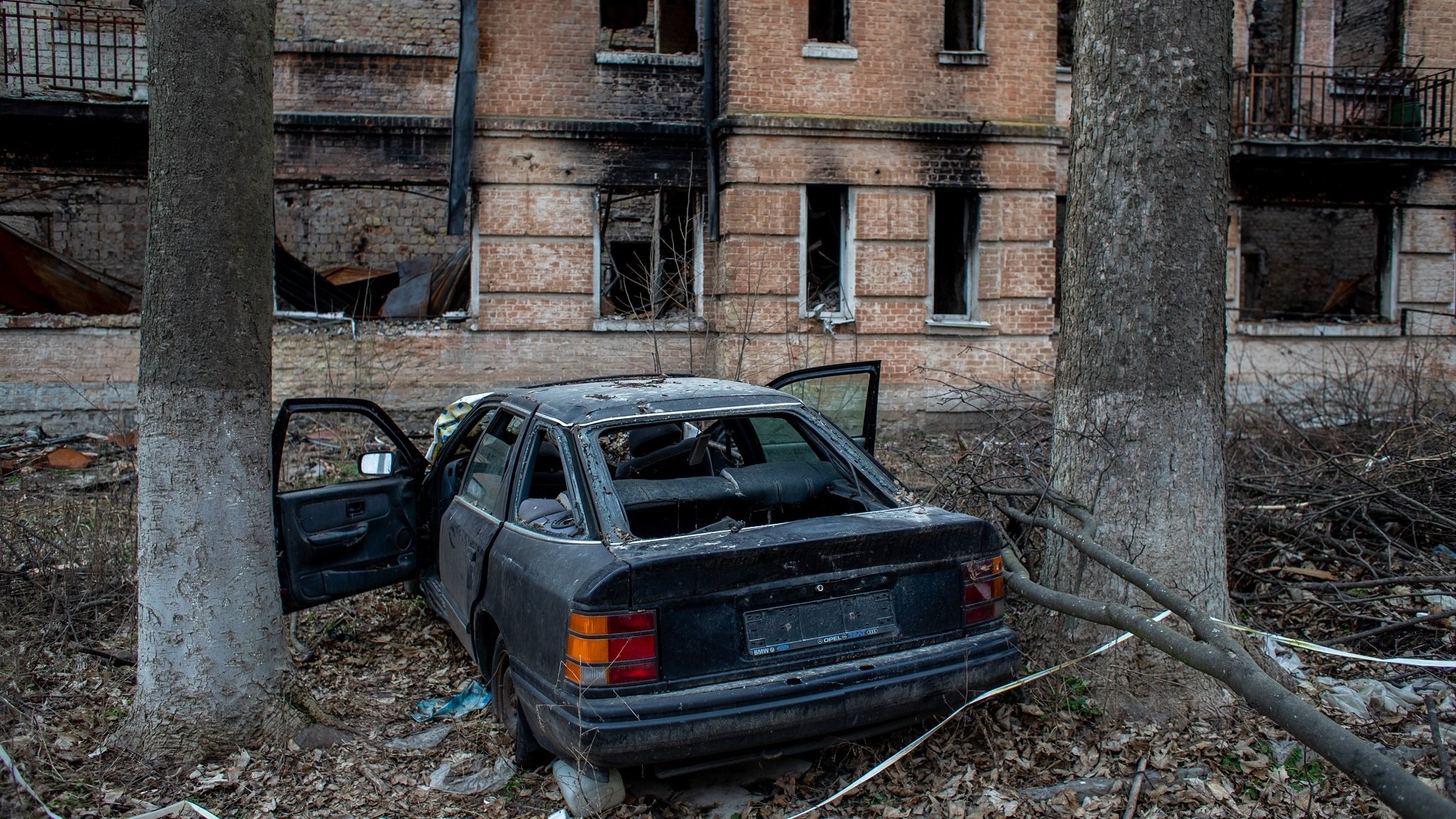 Zerstörtes Auto und zerbombte Häuser in Hostomel (Feb. 2023)
