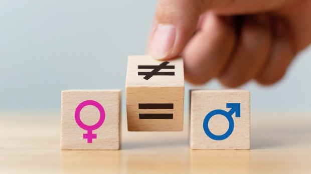 Symbole für Frau, Mann sowie Gleich- und Ungleichzeichen auf Holzwürfeln