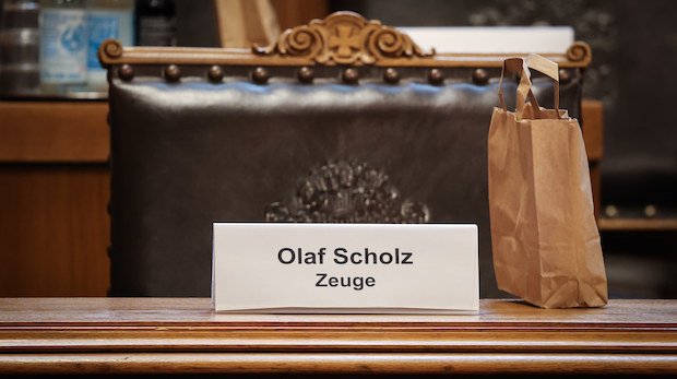 Sitzplatz im Hamburger Parlament. Davor ein Schild mit der Aufschrift "Olaf Scholz Zeuge".