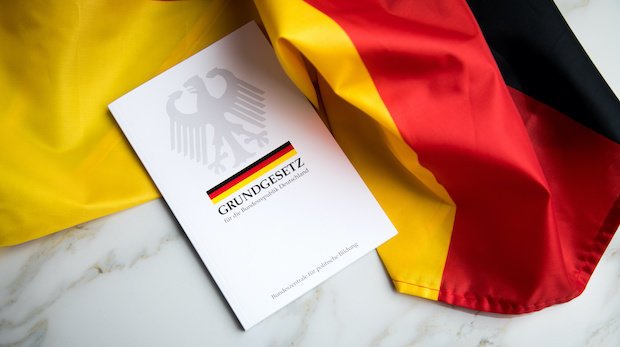 Das Grundgesetz auf der schwarz-rot-goldenen Deuschlandfahne.