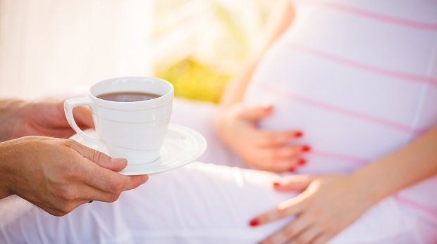Schwangerer Frau wird ein Tee gereicht