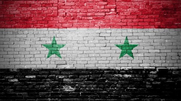 Ziegelsteinmauer mit Flagge Syrien