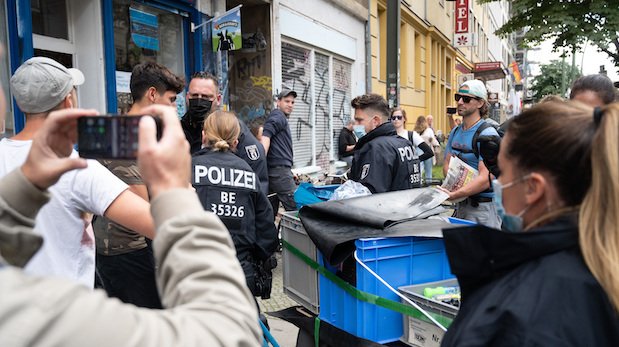 Ein Mann filmt, wie Polizisten Demonstranten gegenüberstehen, die aus Protest gegen die Corona-Politik durch Berlin ziehen.