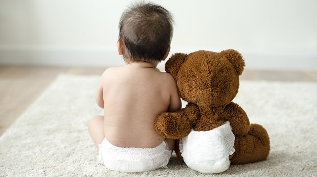 Babyrücken mit Teddybär auf Teppich