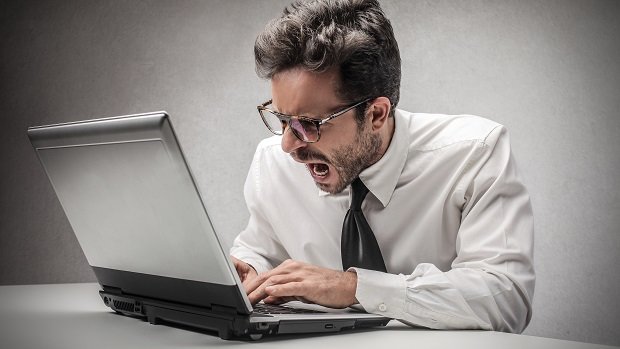 Ein wütender Mann vor einem Laptop.