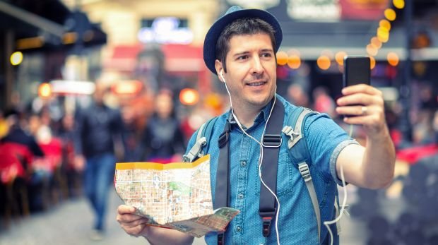 Tourist mit Handy und Straßenkarte in Hand