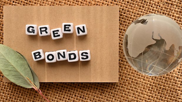 Aufgereihte Wortwürfel mit der Aufschrift 'Green Bonds', daneben zwei Blätter und eine Erdkugel aus Glas
