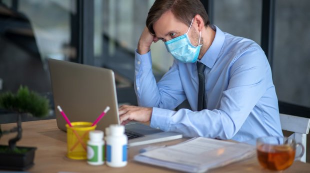 Mann mit Atemschutzmaske im Büro (Symbolbild)