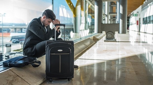 Wartender Mann mit Gepäck am Flughafen (Symbolbild)