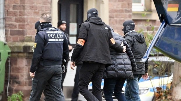 Eine Person (2.v.r.) wird von Polizisten aus einem Hubschrauber gebracht. Die Bundesanwaltschaft hat am Mittwochmorgen mehrere Menschen aus der sogenannten "Reichsbürgerszene" im Zuge einer Razzia festnehmen lassen.