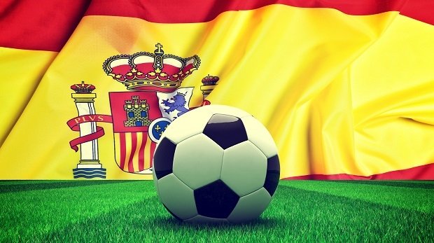 Fußball auf Rasen vor spanischer Flagge
