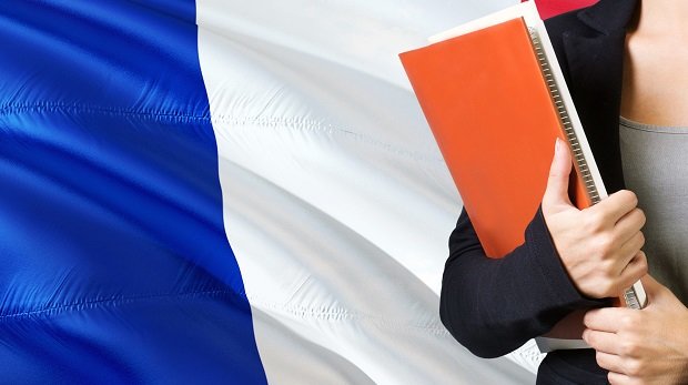 Frau mit Unterlagen vor franzöischer Flagge