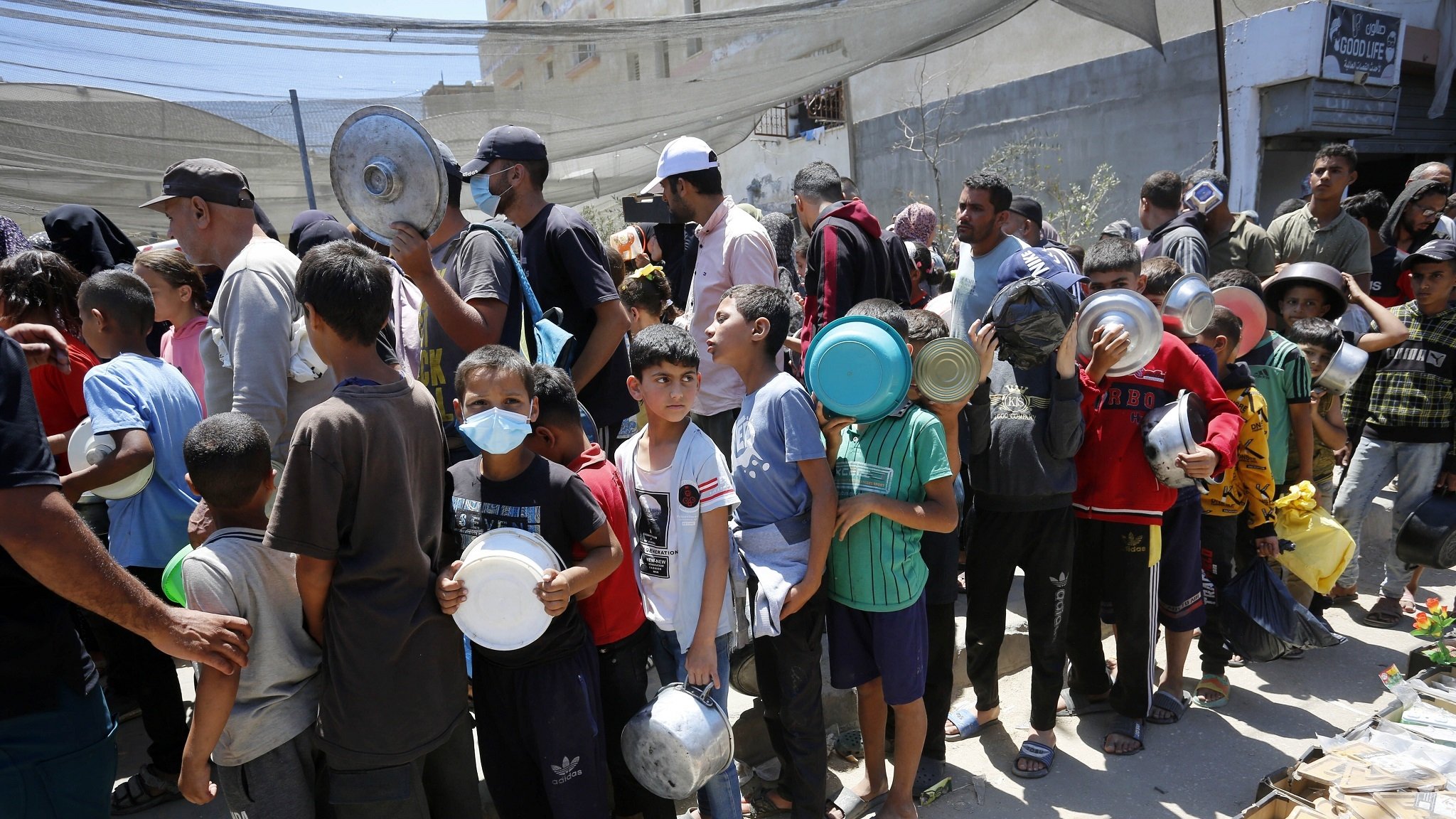 Palästinenser, die aus Rafah vertrieben wurden, warten in langen Schlangen auf Lebensmittel, die Mitarbeiter von Hilfsorganisationen am 13. Mai 2024 in in Deir al-Balah, Gaza, verteilen,