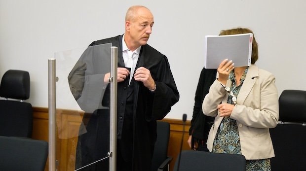 Die Angeklagte (r) steht mit Handschellen im Saal vom Landgericht neben ihrem Verteidiger, Norbert Lösing.