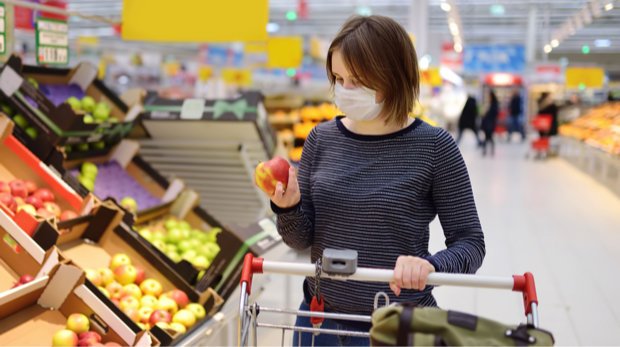 Eine Frau kauft mit Mundschutz im Supermarkt ein