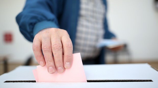 Mann wirft Stimmzettel in Wahlurne