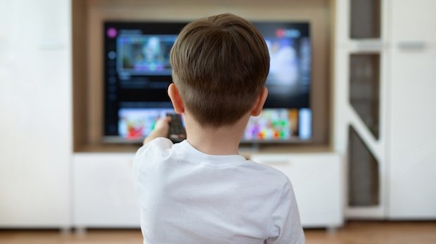 Kind mit Fernbedienung vor Fernseher