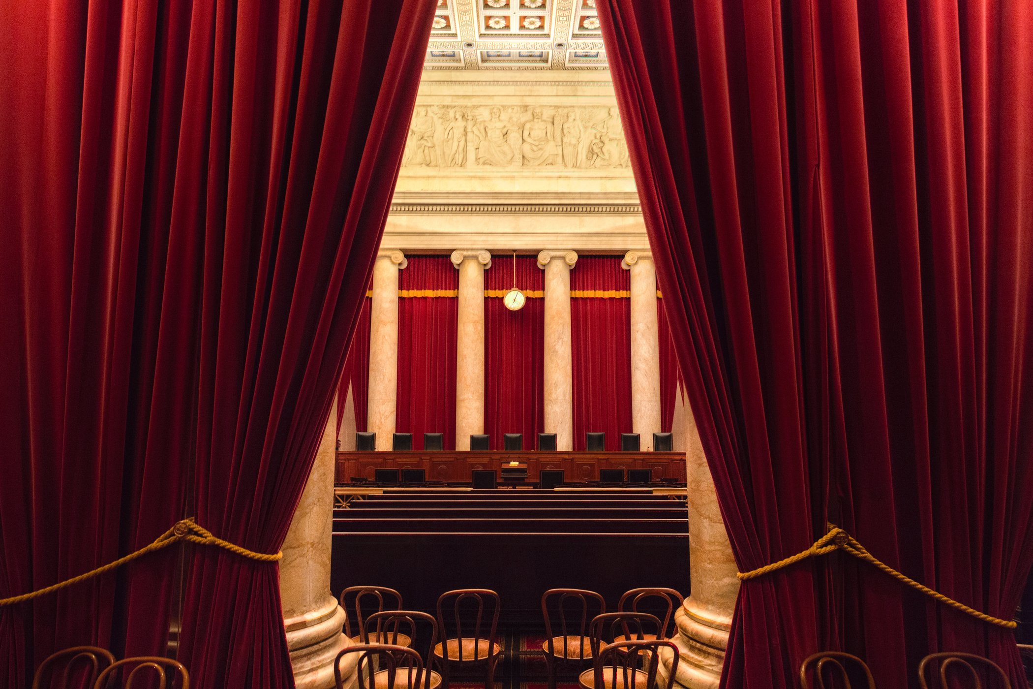 Blick auf Kammer des Supreme Court in den USA durch einen roten Vorhang