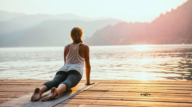 Frau macht Yoga an einem See