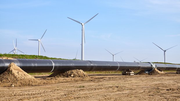 In Bau befindliche Pipeline mit Windrädern im Hintergrund