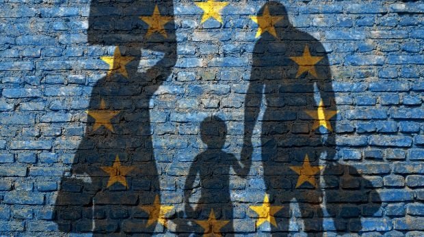 Flüchtlingsfamilie vor einer Wand mit EU-Flagge