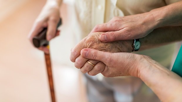 Pflegekraft hält die Hand von einer älteren Patientin
