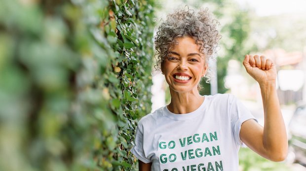 Vegane Aktivistin streckt lächelnd eine Faust in die Höhe