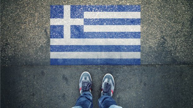 Griechische Flagge auf Straße gemalt. Ein paar Füße stehen davor.