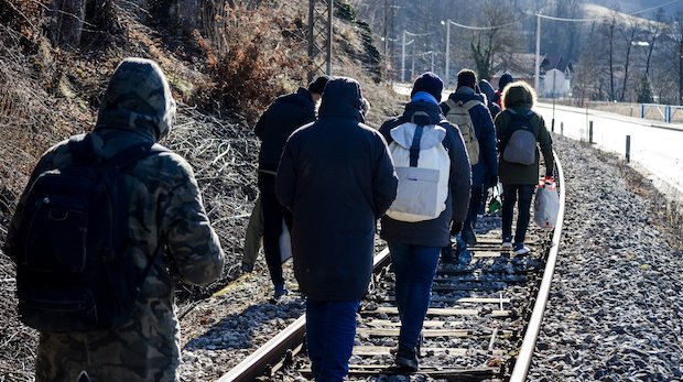Eine Gruppe von Migranten läuft auf Schienen.