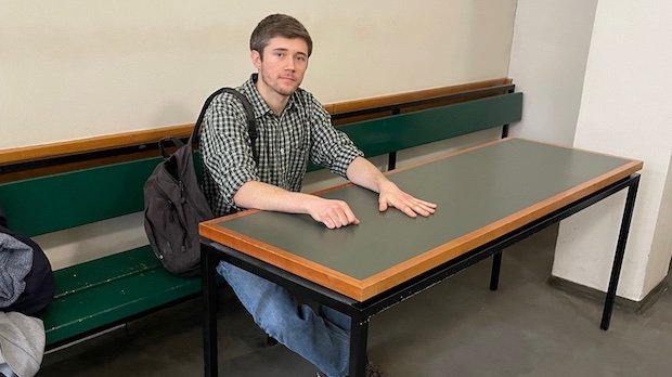 Klimaaktivist Henning Jeschke sitzt festgeklebt an einem Tisch in einem Raum des Amtsgericht Tiergarten.