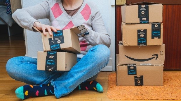 Person mit bunten Socken öffnet sitzend Pakete von Amazon