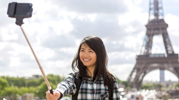Eine Asiatin macht einen Selfie vor dem Eifelturm