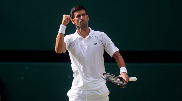 Novak Djokovic reckt bei einem Tennisspiel den Arm in die Luft.