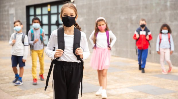 Kinder mit Masken vor der Schule